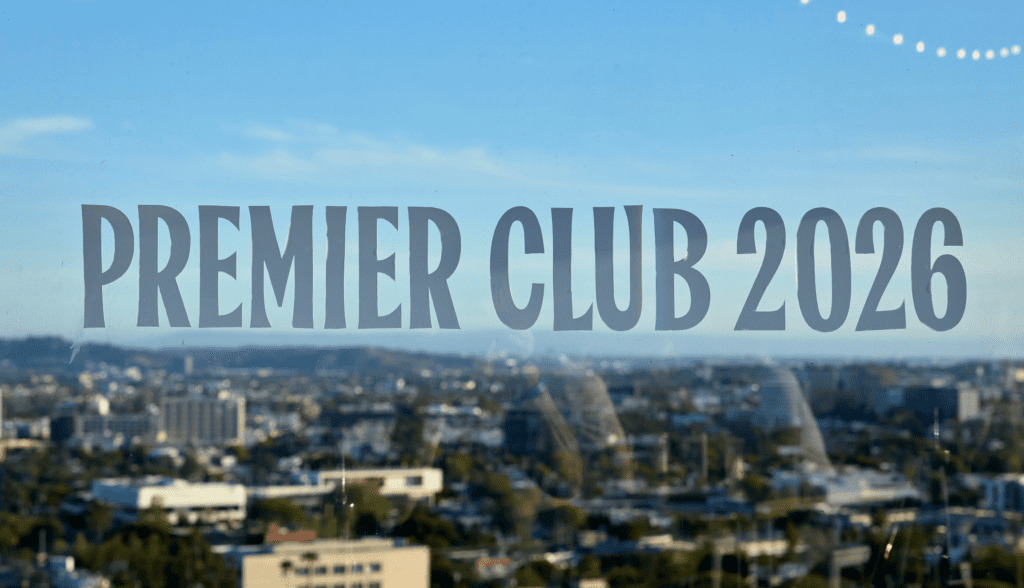 Large text reading PREMIER CLUB 2026 is displayed on a glass window, with a cityscape and blue sky in the background, symbolising shared experiences awaiting future members.