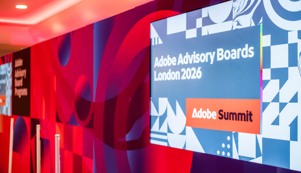 A digital screen displays Adobe Advisory Boards London 2026 and Adobe Summit on a colourful geometric background at an advisory board event venue.